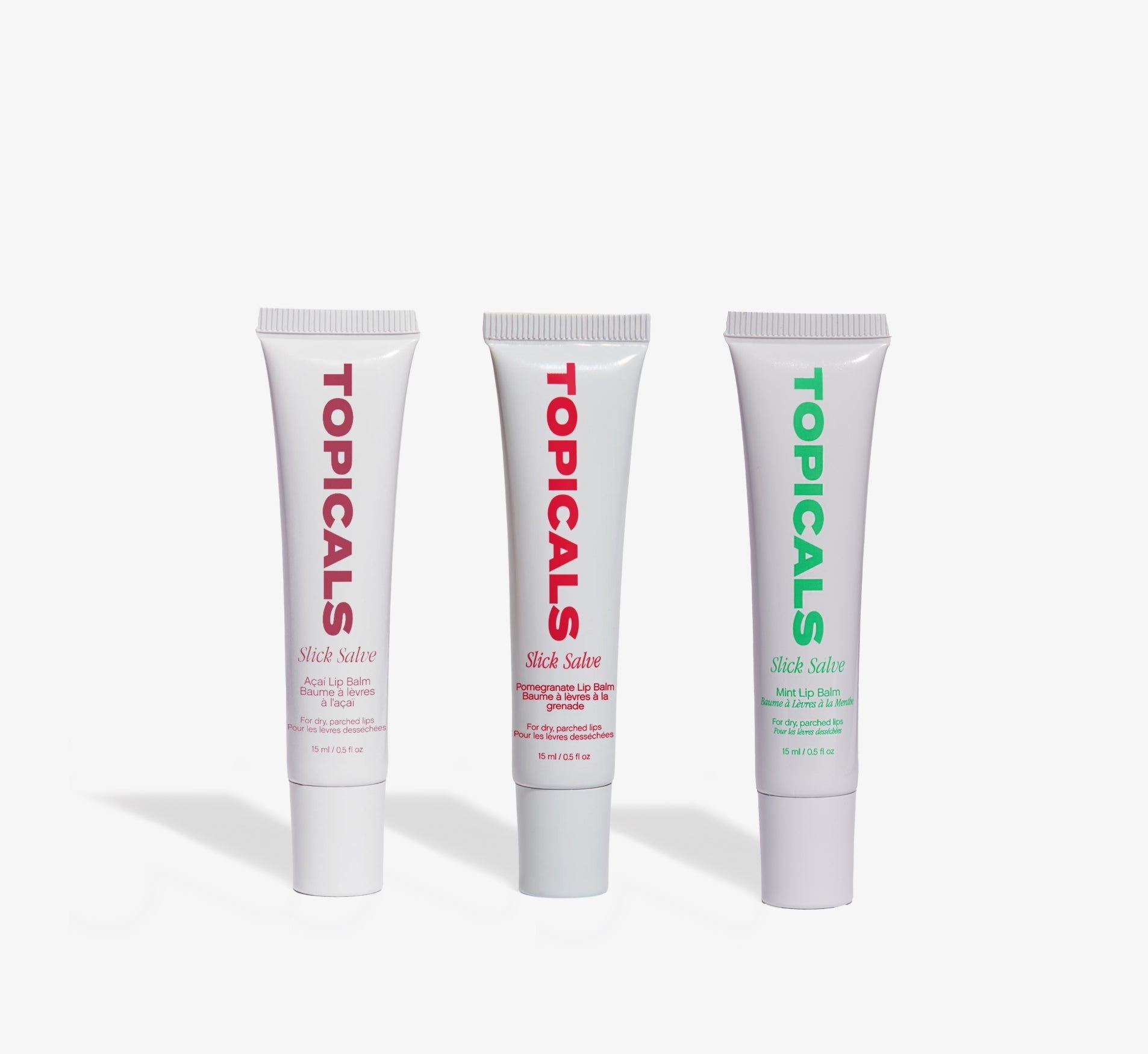 Moisturizing lip balm trio from Topicals Slick Salve in Açaí, Pomegranate, and Mint standing upright side by side on a white background.